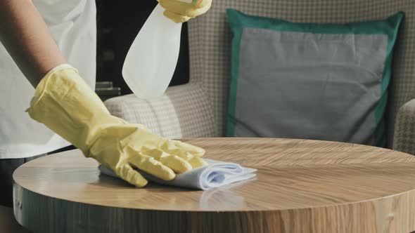 Gloved Hands of Housekeeper Cleaning Table in Hotel Room