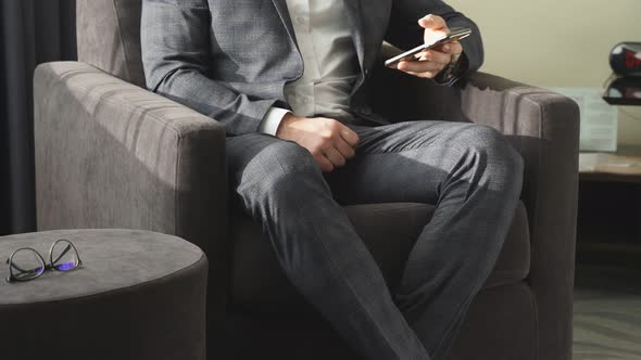 Business Man with Mobile Phone Sitting on Couch