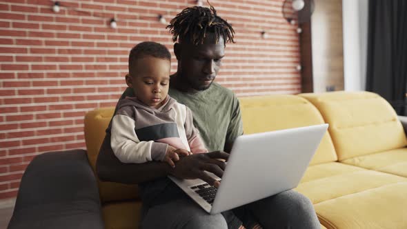 Young African American Dad Teaching Little Focused Kid Son Use Laptop