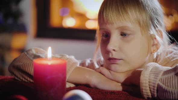 Portrait of a Scattered Child Looking at a Candle Against a Fireplace