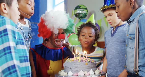 Kids with clown blowing candles on cake during birthday party 4k