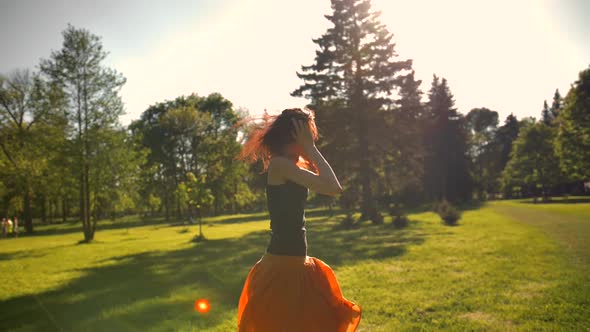 Beautiful Redhead Lady with Long Hair Enjoys Music with Earphones.