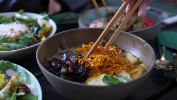 Close Up of Chopsticks Mixing Ingredients in Healthy Vegan Soup. Healthy Asian Street Food Concept