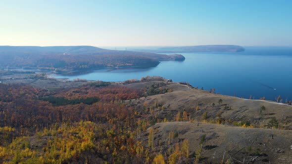 Aerial drone flight over the autumn forest in the mountains to the river bay