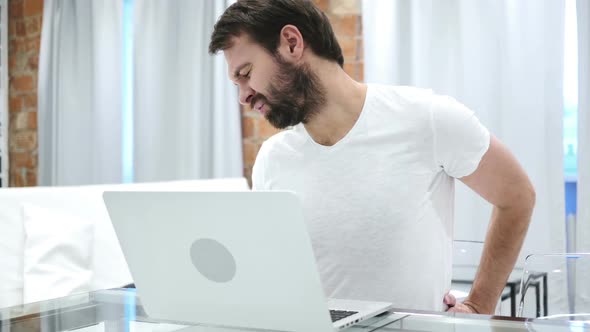 Beard Man with Back Pain Trying to Relax on Couch at Home