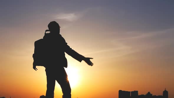 Silhouette of a Man with a Backpack Against Bright Sky Sunset alt