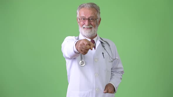 Handsome Senior Bearded Man Doctor Against Green Background