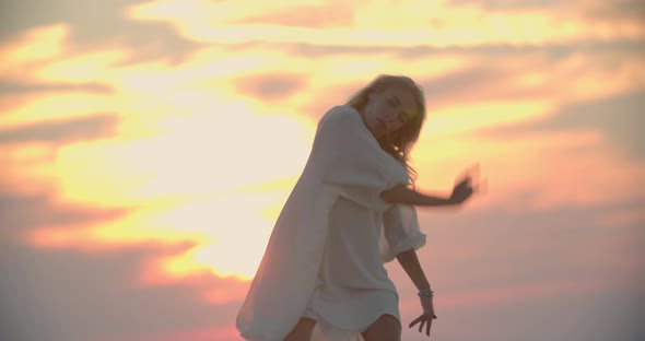 Happy Young Woman is Dancing on the Pier of a Lake During Amazing Sunset