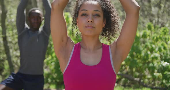 Diverse couple practicing yoga and posing in countryside