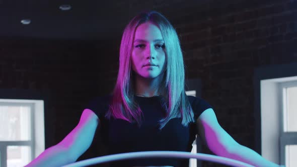 Young Pretty Blonde Woman Gymnast Playing with a Hoop in Neon Purple Lighting