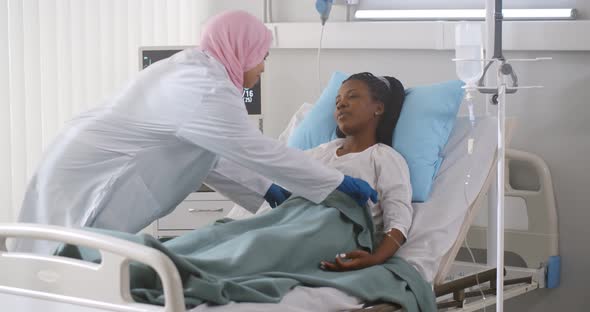 Arabian Nurse Taking Care and Checking Up African Female Patient in Hospital Ward