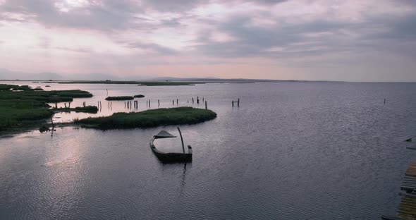 Sunrise over lake coastline with wooden pier.