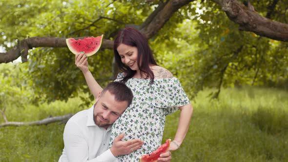 Handsome Man Kissing Pregnant Belly of His Charming Wife on Fresh Air