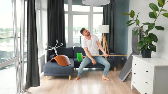 Man Does the Cleaning and Imagines Himself a Rock Star Plays the Broom Like a Guitar