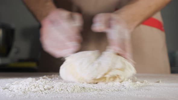 Chef Baker Kneads Dough with Flour on the Table