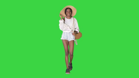 Relaxed African American Girl Walking Wearing a Straw Hat and a Bag on a Green Screen, Chroma Key