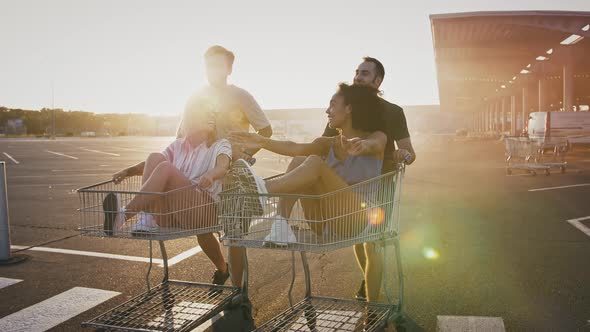 Young Guys are Walking Pushing Shopping Trolleys with Their Multiracial Girlfriends at Deserted