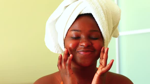 Hispanic Woman with Towel on Head Applying Cream on Face at Home