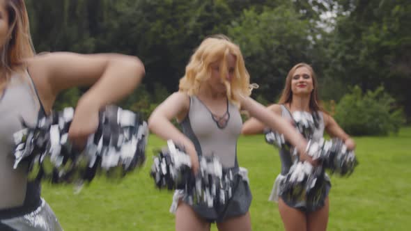 Young Cheerful Girls with Pom Poms Dancing Outdoors