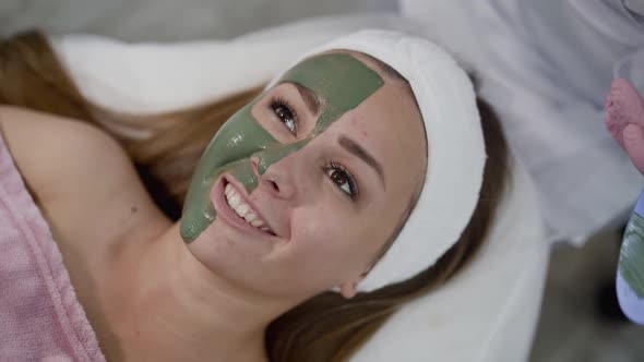 Healthy Girl Lying with Mask of Green Clay on Face and Relaxes During Treatment