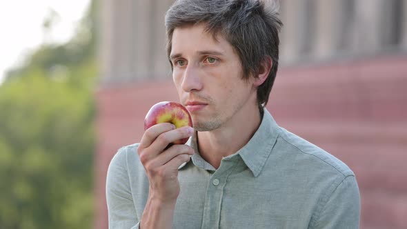 Young Attractive Cheerful Man Holding Apple in Hand Sniffing Ripe Fruit Discovers Absence of Smell