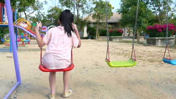 Sad Asian Girl Playing Swing In The Park