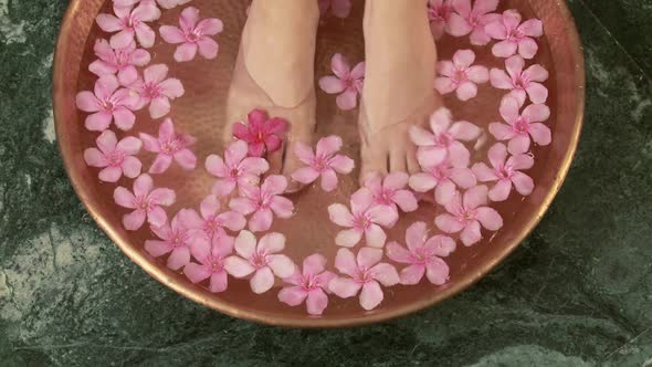 Woman placing feet in bowl of water and flowers