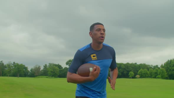 Determined Sporty Black American Football Player with Ball Running on Field