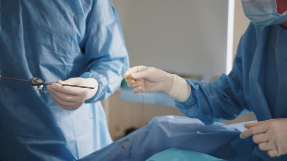 A Team of Surgeons Stitches the Patient's Skin Using a Needle Holder and