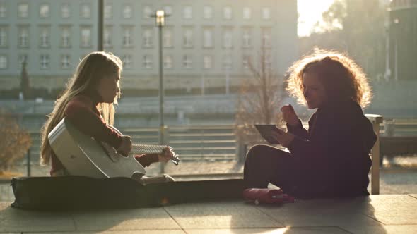 Teenage Girls Sitting on the City Embankment