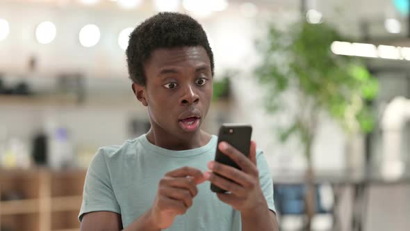 Young African Man Having Loss on Smartphone 