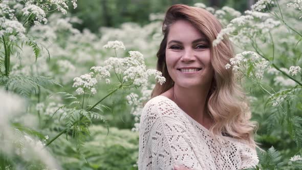 Young Woman Among White Flowers in the Forest Enjoying Nature and Freshness in Summer