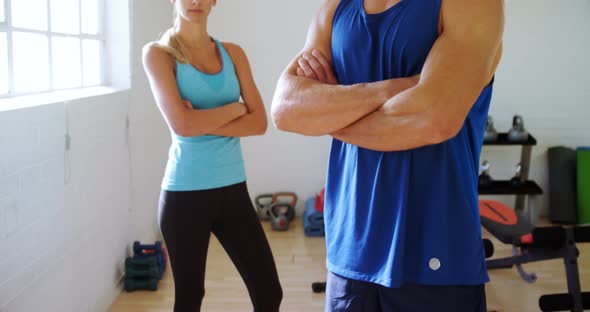 Man and woman with hands crossed standing in gym 