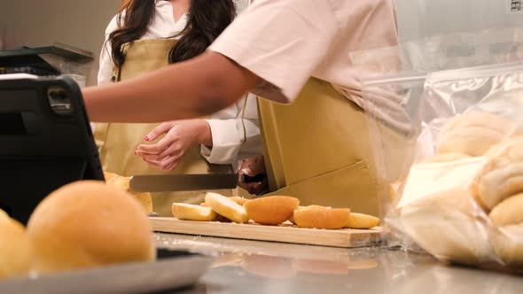 Two startup chefs live stream show, demonstrate slicing bread in the kitchen.