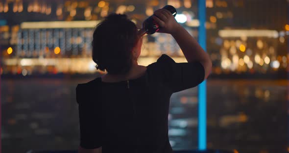 Back View of Drunk Woman Standing Near Panoramic Window and Drinking Wine Having Depression