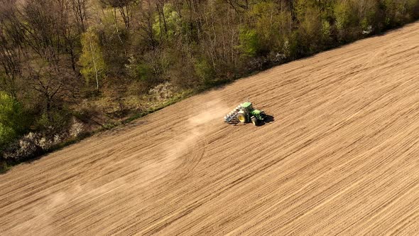 Aerial view large tractor cultivating a dry field. Top down aerial view tractor cultivating ground