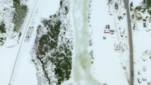 Frozen River Flowing Between Forest And Village At Haugastol At Wintertime In Norway. - aerial