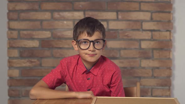Child Sitting at the Desk Holding Flipchart with Lettering Sale on the Background Red Brick Wall