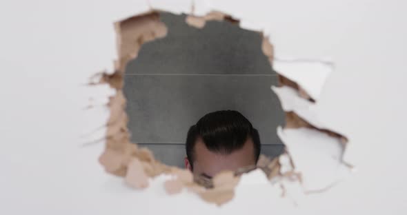 Young Man Raises His Head and Sees That Someone is Watching Him Through a Hole Punched in
