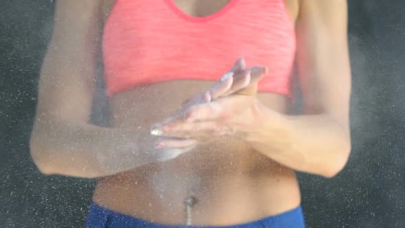 Muscular Woman Clapping Hands with Talc Powder in a Gym.