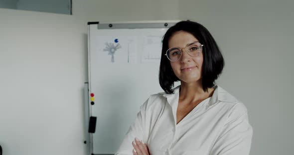 Portrait of Confident Teacher Corrects Glasses and Smiles at Camera in Office