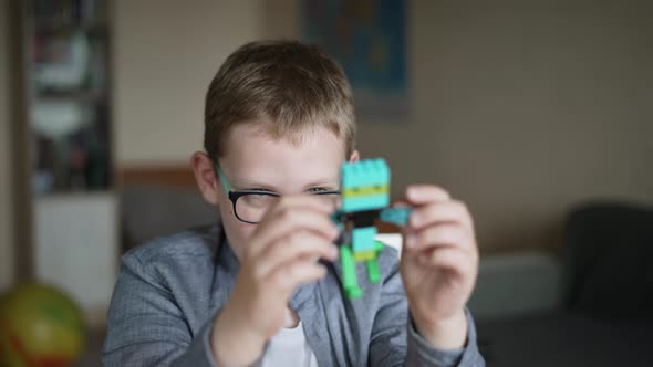 Child in Glasses Twists Colored Toy Built Constructor Bricks in Front of Face