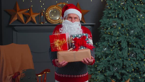 Senior Grandfather Parodies Santa Claus Presenting Christmas Gift Box Holidays Celebration at Home