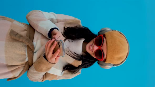 Cheerful Woman in Headphones Browsing Smartphone Blue Background