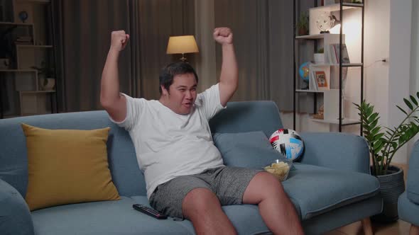 Excited Asian Fat Man Watches Tv In Living Room
