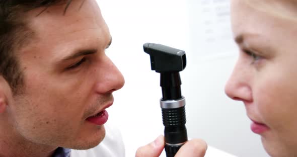 Optometrist examining female patient through ophthalmoscope