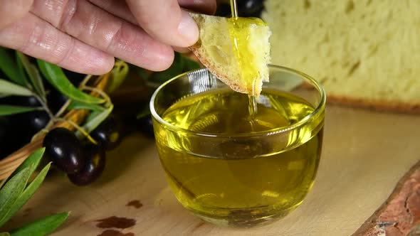 A fresh organic cold pressed olive oil pouring on a piece of bread that a hand holding