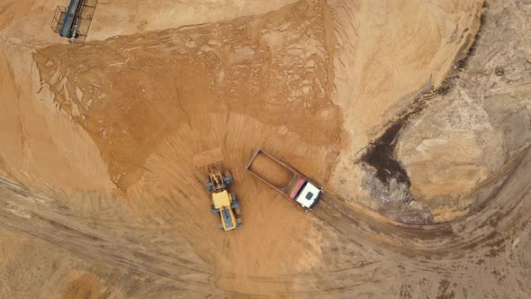 Loader load sand into dump trucks