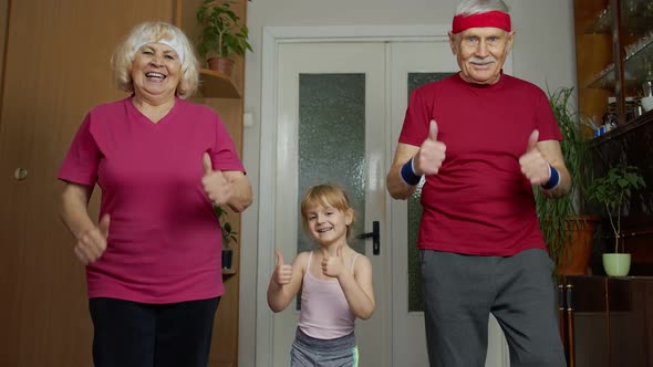 Granddaughter and Mature Grandparents in Sportswear Making Sports Jogging Workout Exercises at Home