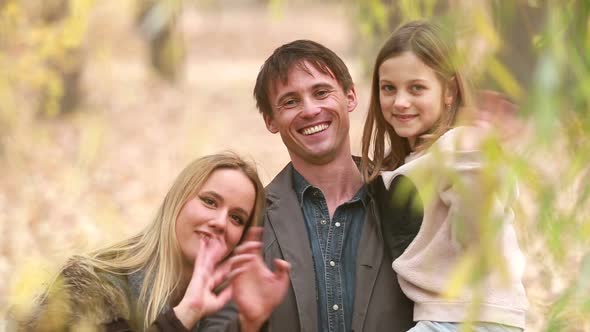 Portrait of family smiling and waving in park